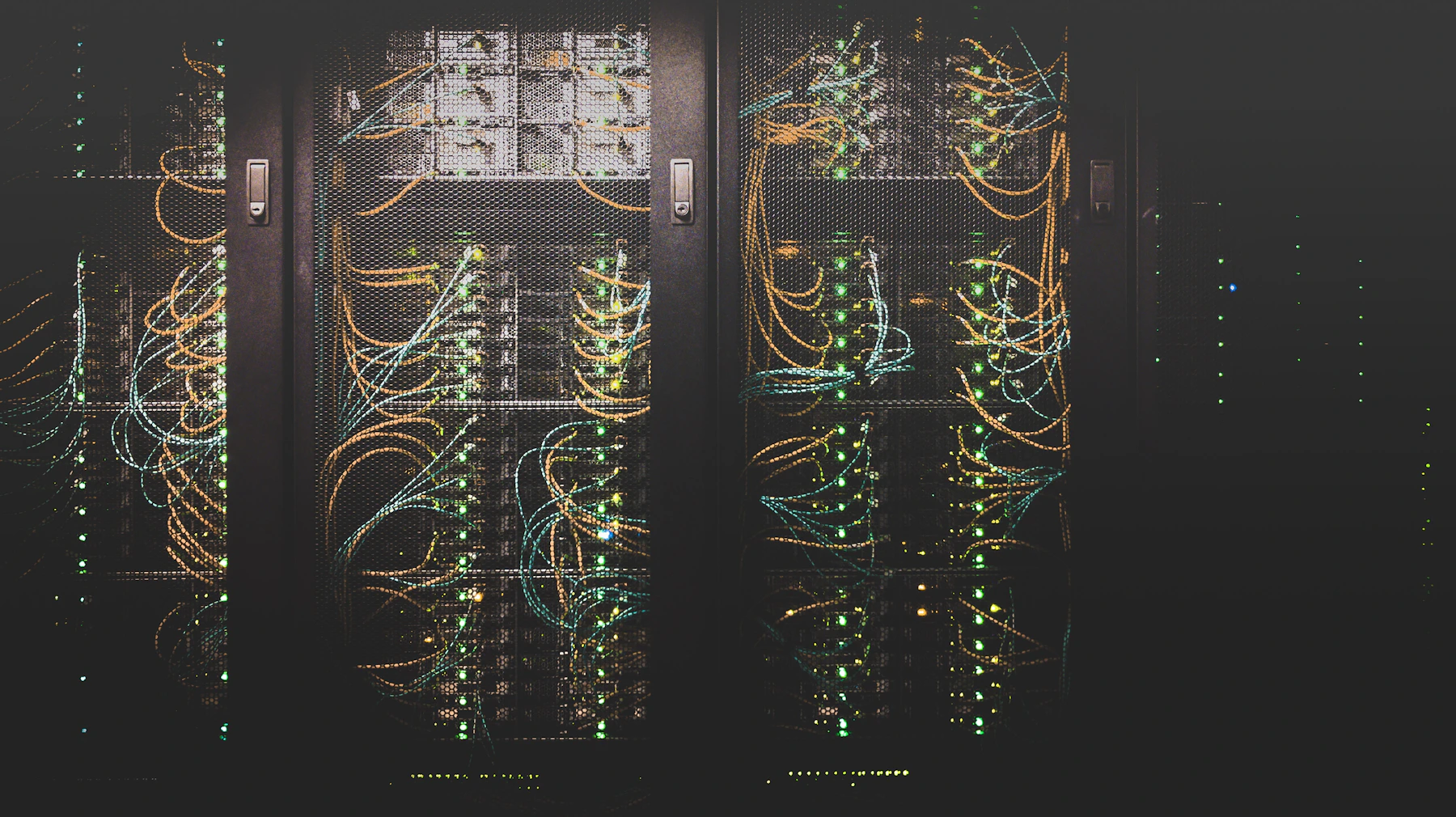 Sala de servidores em penumbra com luzes de status vermelhas e azuis